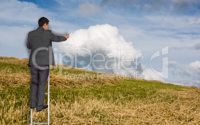 Composite image of businessman standing on ladder