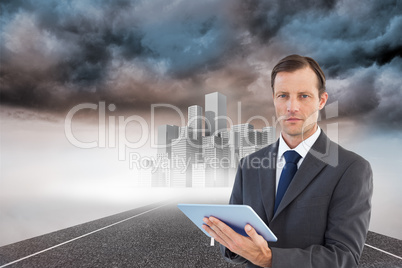 Composite image of serious charismatic businessman holding a tab