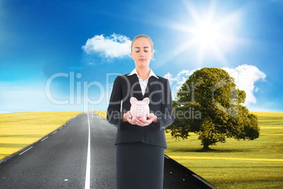 Composite image of businesswoman holding pink piggy bank