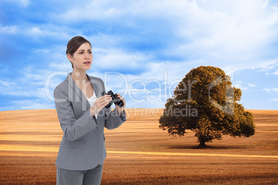 Composite image of curious young businesswoman with binoculars