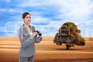 Composite image of curious young businesswoman with binoculars