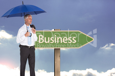 Composite image of happy businessman holding umbrella