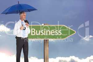 Composite image of happy businessman holding umbrella