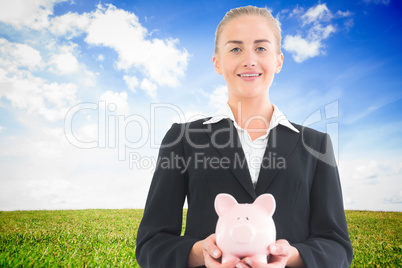 Composite image of businesswoman holding piggy bank