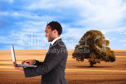 Composite image of businessman working on laptop