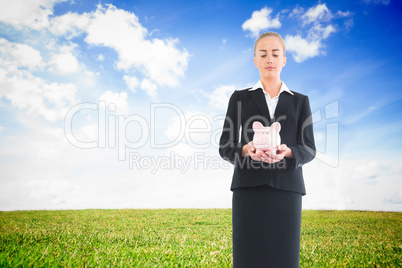 Composite image of businesswoman holding pink piggy bank