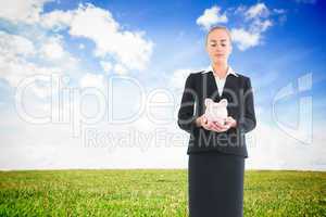 Composite image of businesswoman holding pink piggy bank