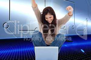 Composite image of brunette cheering while using laptop