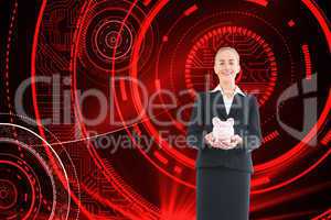 Composite image of businesswoman holding pink piggy bank