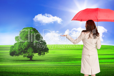 Composite image of businesswoman holding umbrella