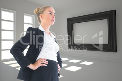 Composite image of businesswoman standing with hands on hips