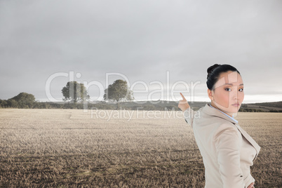 Composite image of unsmiling asian businesswoman pointing