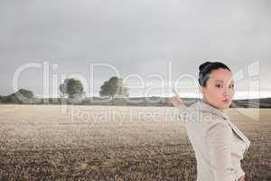 Composite image of unsmiling asian businesswoman pointing