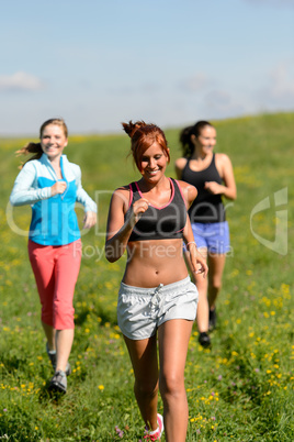 three girls jogging downhill summer meadow