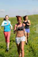 three girls jogging downhill summer meadow