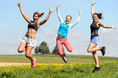 sporty friends jumping cheerful on sunny meadow
