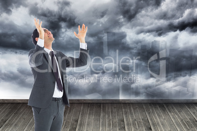 Composite image of happy businessman with arms raised