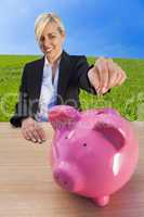woman putting money into pink piggy bank