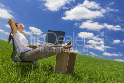 woman relaxing at office desk in green field