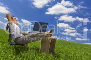 woman relaxing at office desk in green field