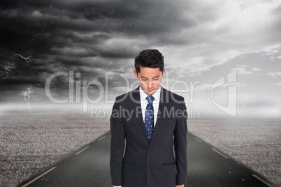 Composite image of serious businessman looking down