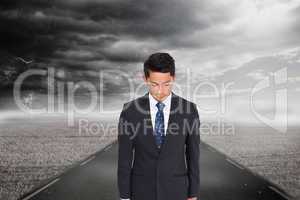 Composite image of serious businessman looking down