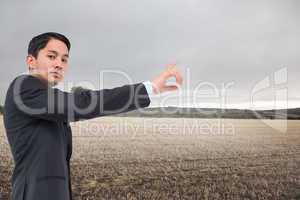 Composite image of serious asian businessman pointing