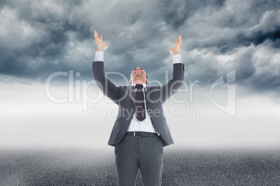 Composite image of businessman with arms raised