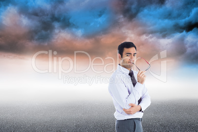 Composite image of thinking businessman holding glasses