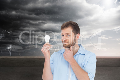 Composite image of handsome model holding a bulb