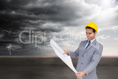 Composite image of smiling architect with hard hat looking at pl