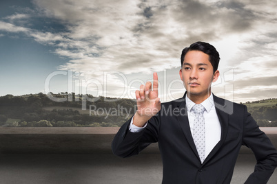 Composite image of unsmiling asian businessman pointing