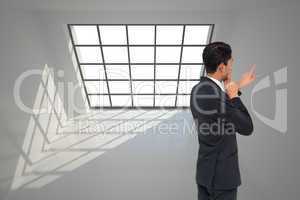 Composite image of thoughtful asian businessman pointing