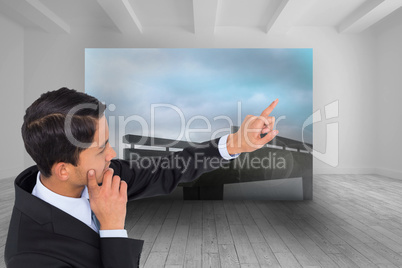 Composite image of thoughtful asian businessman pointing