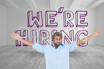 Handsome man raising arms in front of were hiring graphic