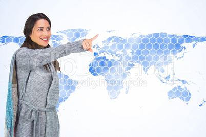 Composite image of smiling brunette wearing winter clothes point