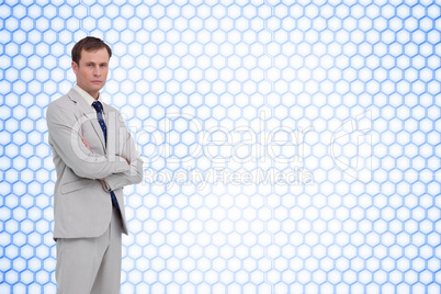 Composite image of serious businessman standing with his arms fo