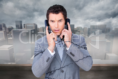 Composite image of angry businessman tangle up in phone wires
