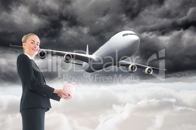 Composite image of businesswoman holding pink piggy bank