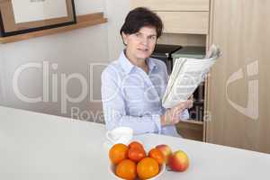 woman relaxing drinking a cup of coffee and reading newspaper