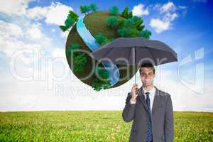 Composite image of happy businessman holding grey umbrella