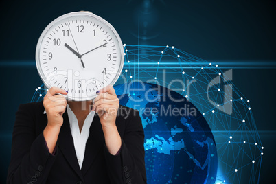 Composite image of businesswoman in suit holding a clock