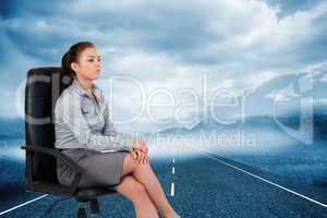 Composite image of portrait of a serious businesswoman sitting o