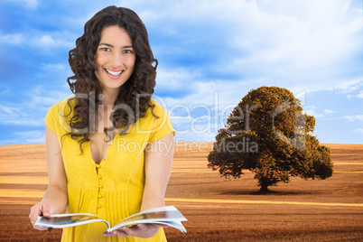 Composite image of cheerful curly haired brunette reading magazi