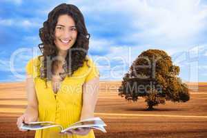 Composite image of cheerful curly haired brunette reading magazi