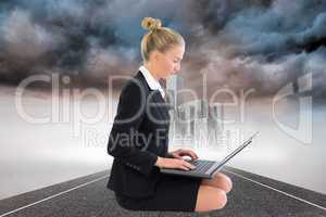 Composite image of businesswoman using laptop