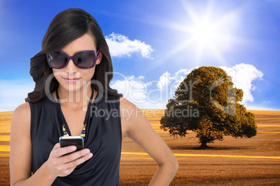 Composite image of happy brunette using smartphone