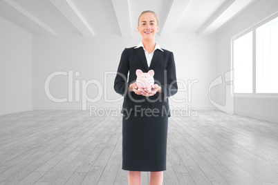 Composite image of businesswoman holding pink piggy bank