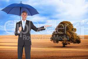 Composite image of peaceful businessman holding blue umbrella