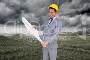 Composite image of smiling architect with hard hat looking at pl